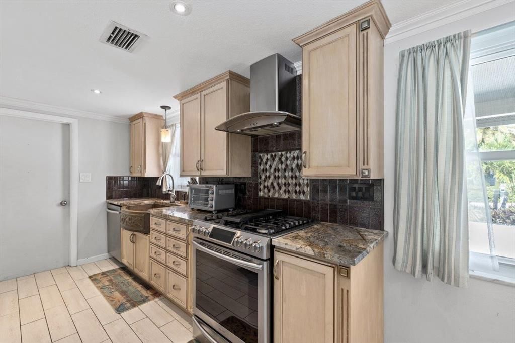 Gourmet kitchen featuring granite counters, custom wood cabinets, stainless steel appliances, and hammered copper farm sink.