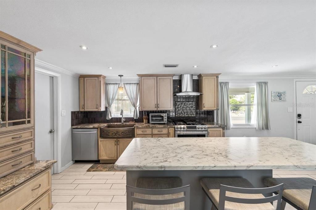 Gourmet kitchen featuring granite counters, custom wood cabinets, stainless steel appliances, and hammered copper farm sink.