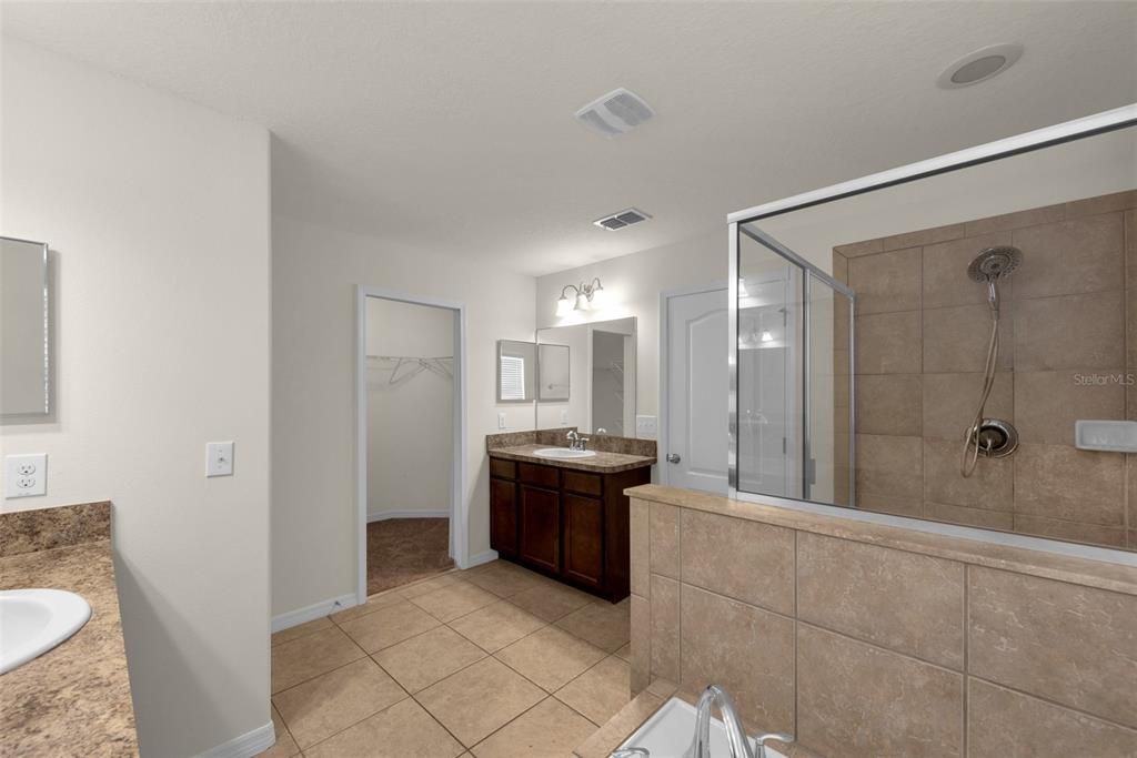 Separate vanities in the Primary Bathroom and access to the walk-in closet.