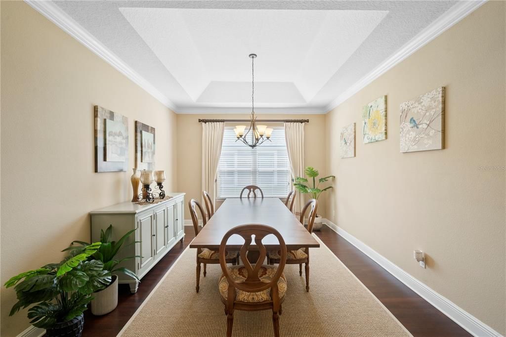 Primary suite includes tray ceiling crown molding, en suite bath and views of the backyard and pool