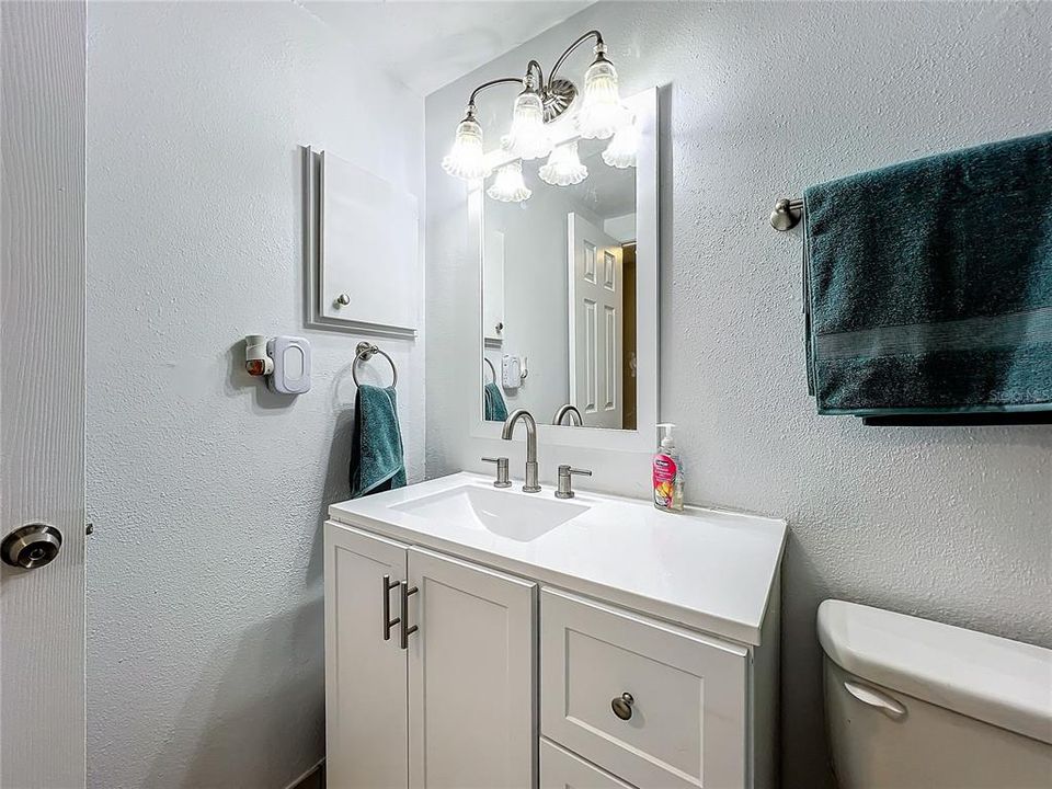 Guest bathroom with updated cabinet, counter, toilet, mirror, and light fixture.