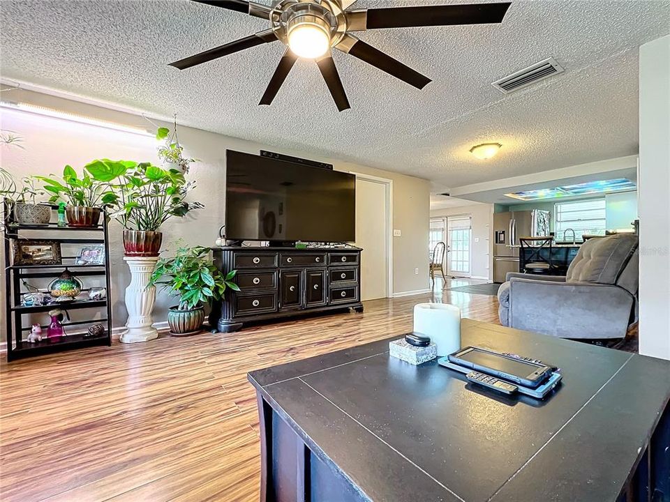 Another view of the great room with updated flooring and ceiling fan.