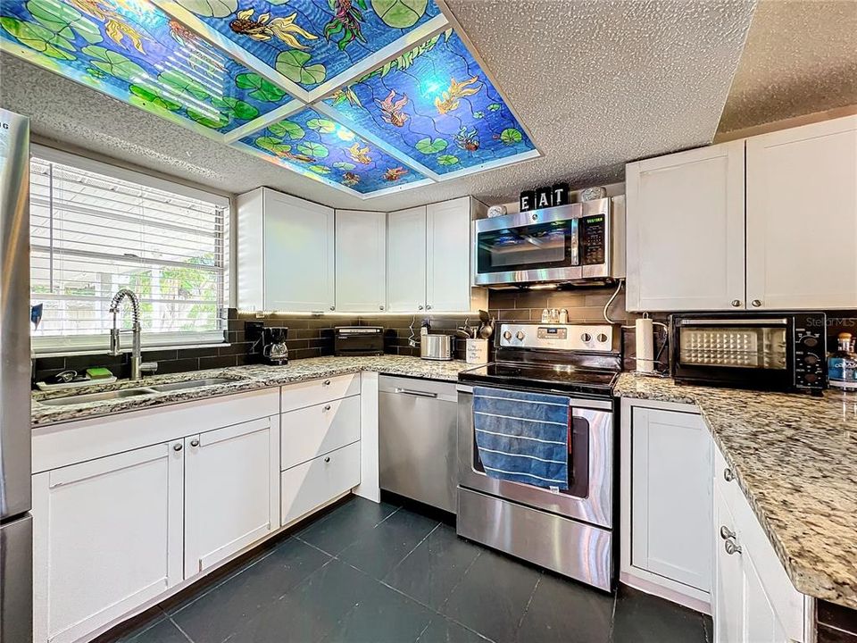 Tile backsplash, white cabinets, stainless steel appliances, granite counters and the Florida sea life adorn this homey kitchen.