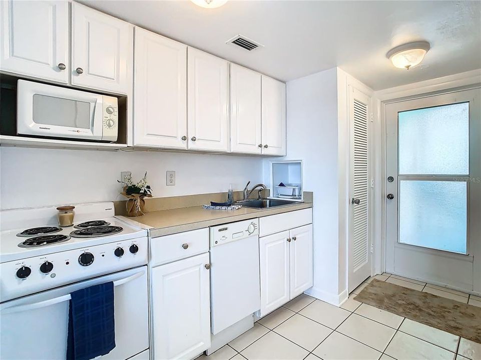 View of kitchenette towards the front door. The louvre door houses the newer HVAC closet. Across from the HVAC closet is the entrance to the lavatory, via barn door.