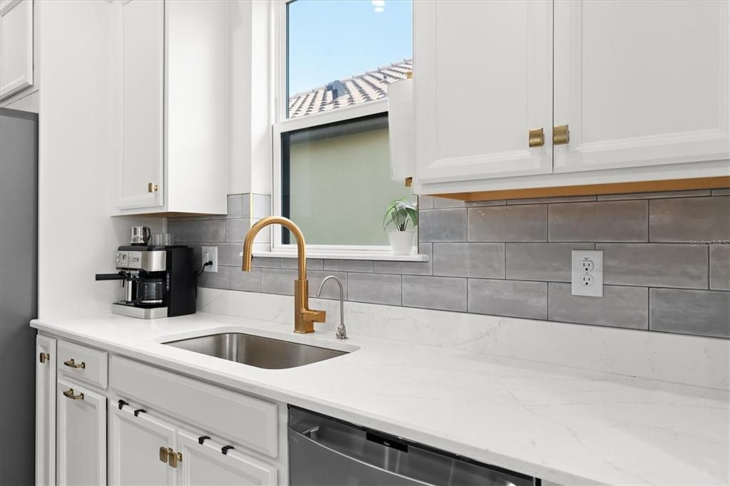 SPACIOUS QUARTZ COUNTERS WITH DESIGNER GOLD HARDWARD AND TOUCHLESS FAUCET