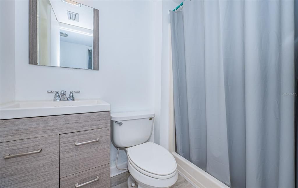 This second bathroom features a single vanity and a spacious shower, combining functionality with a sleek design.