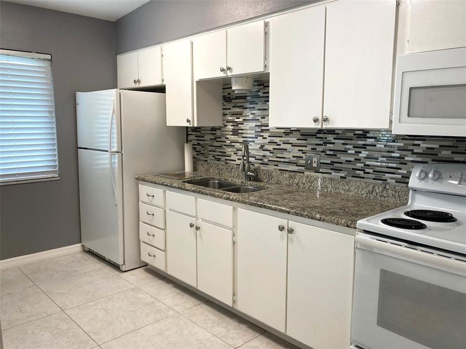 Galley style kitchen with updated countertops and backsplash.