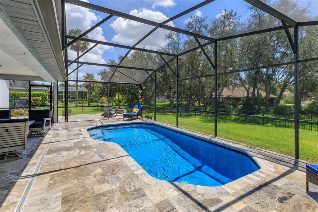 Travertine pavers surround the screened pool