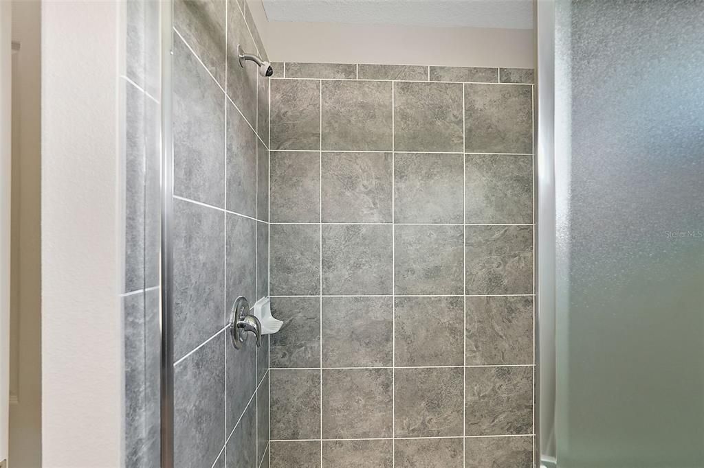 Walk in Shower with glass slider doors, ceramic tile floor & walls.