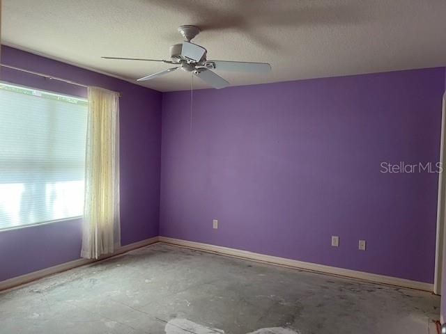 Primary bedroom with ensuite bath, ceiling fan, exposed concrete flooring