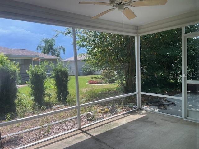 Screen enclosed lanai with ceiling fan and concrete floor