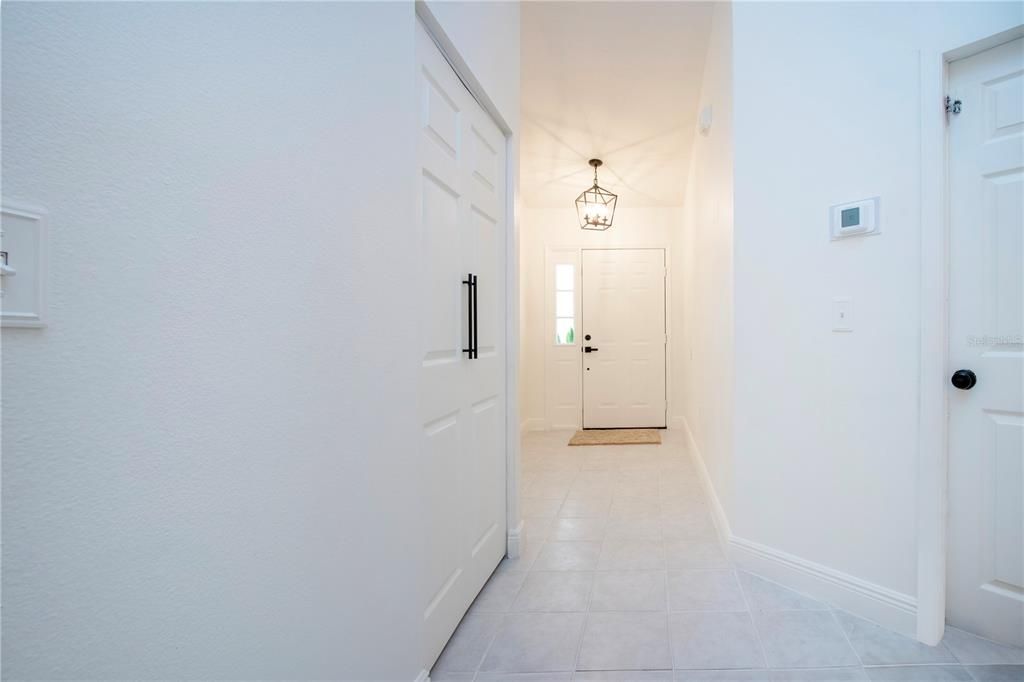 Hallway to the front door coat closet to the left and door to the garage is to the right