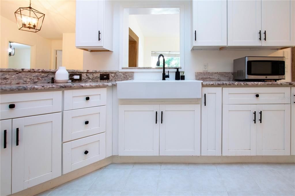 updated kitchen showing the large open farm sink and service window to the enclosed lanai