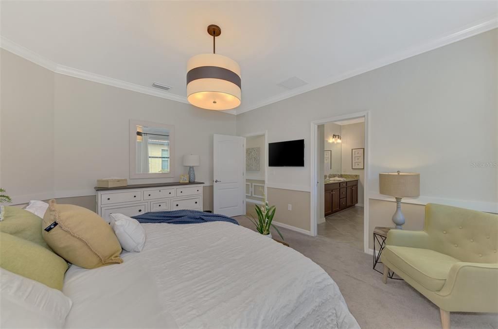 The large master bedroom has a king bed, dresser, chair and tables.