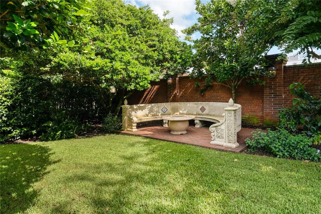 Serene park-like side yard with built in bench and a natural gas fire pit