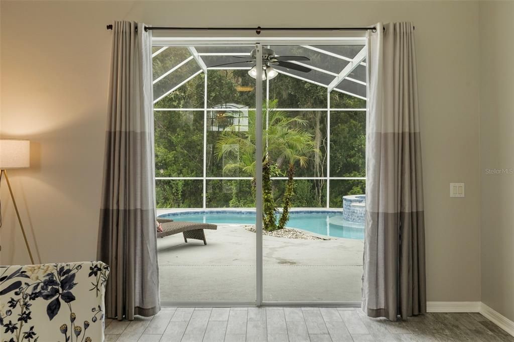 Living Room Sliding Doors Leading out to Screened in Lanai with Pool and Spa