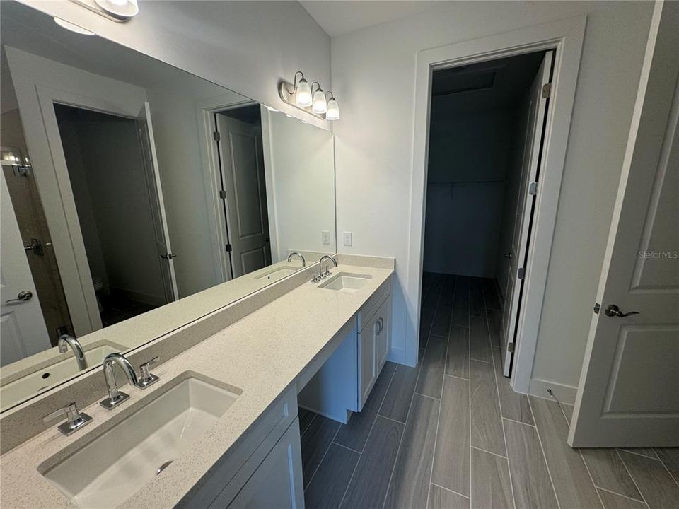 Primary bathroom with dual-sinks, luxe walk-in shower and walk-in closet pictured in back