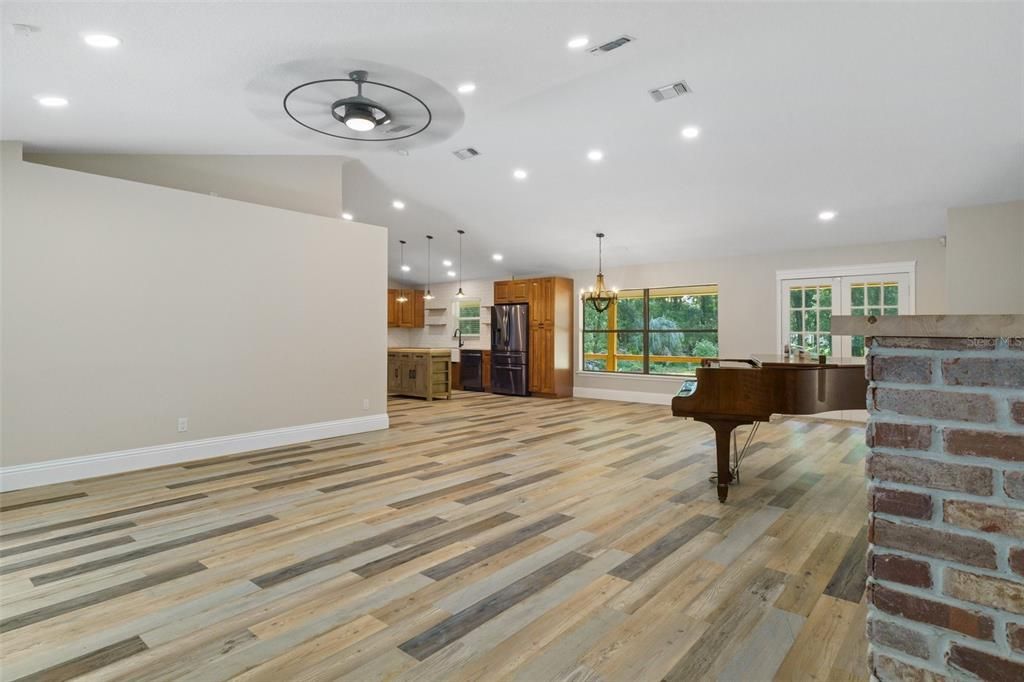 Large living room in center of home with vaulted ceilings and views outside on both sides of the home.