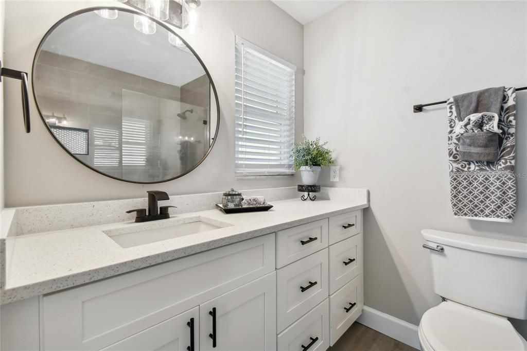 Primary bathroom has been completely remodeled with new vanity, quartz countertop, faucet, light, mirror, toilet, shower tile and glass enclosure. Lots of storage!