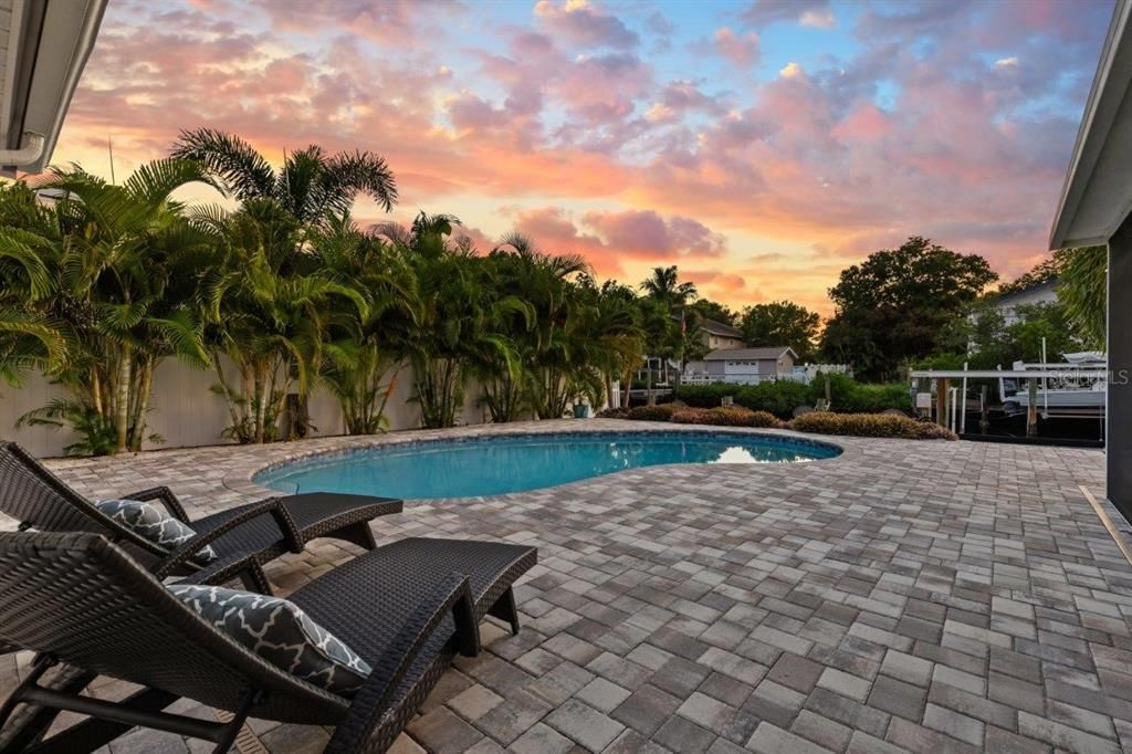 Extended paver patio and open pool backing up to the canal.