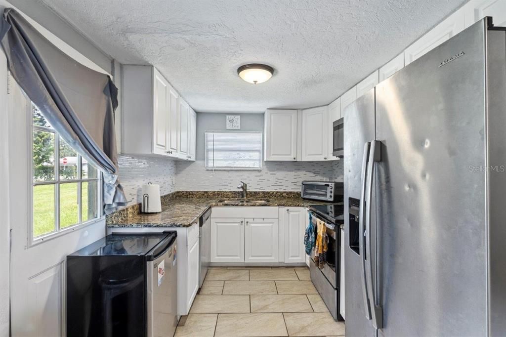 Galley-Style kitchen featuring granite countertops, ample cabinetry, stainless steel appliances, and a dinette.