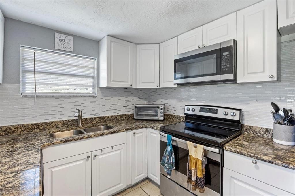 Galley-Style kitchen featuring granite countertops, ample cabinetry, stainless steel appliances, and a dinette.