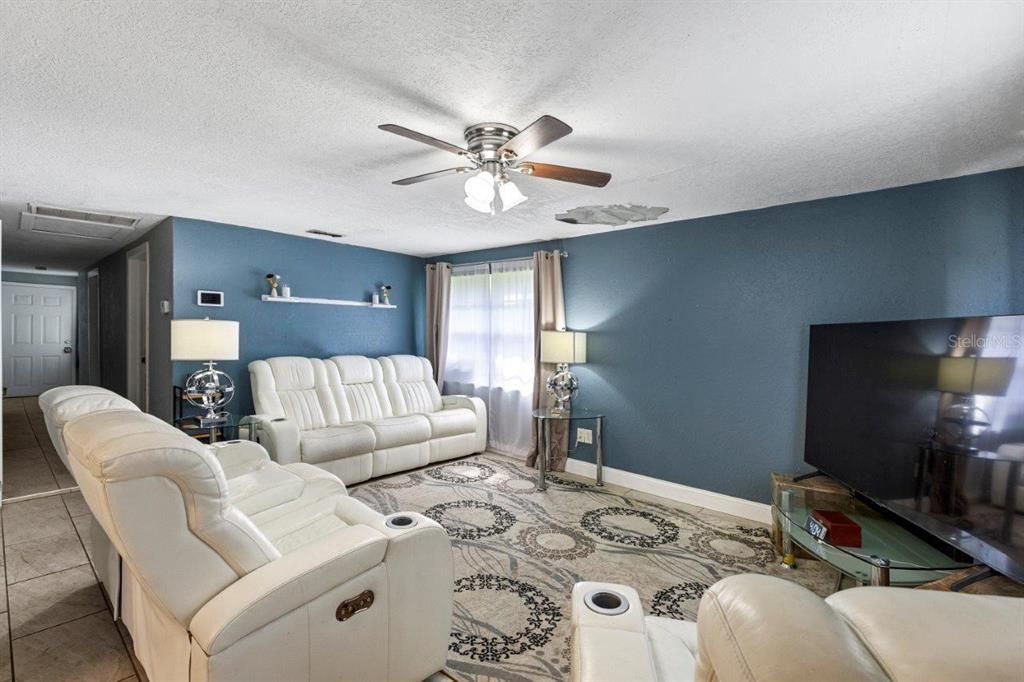 Spacious living room featuring large windows and ceramic tile floors throughout.