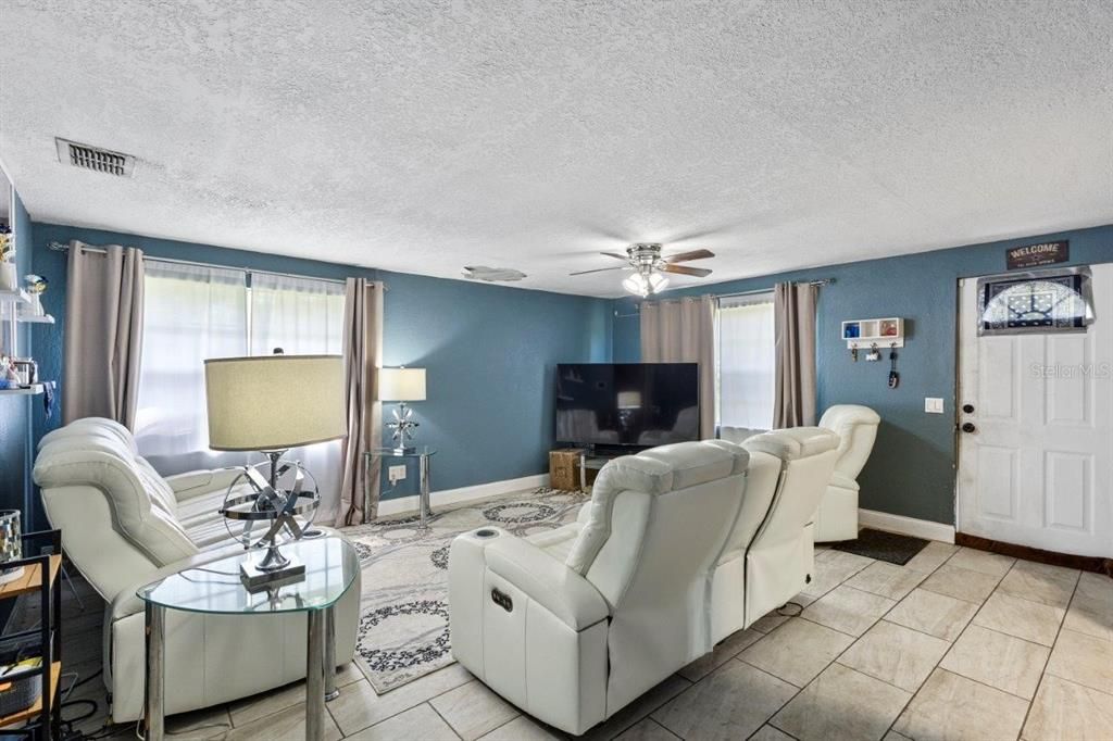 Spacious living room featuring large windows and ceramic tile floors throughout.