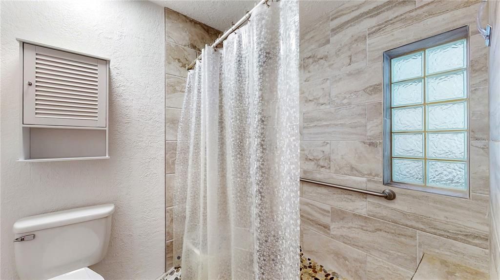 Full shower is equipt with a bench seat and glass block window for privacy and light