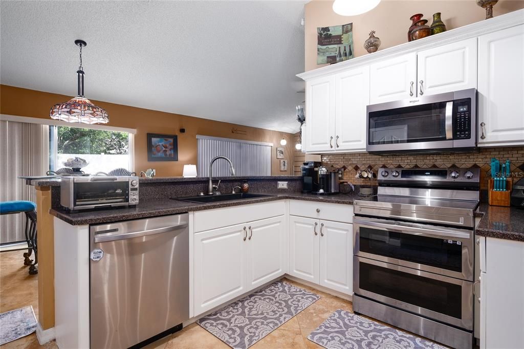 Kitchen includes all stainless steel appliances. Dining/main living area afar.