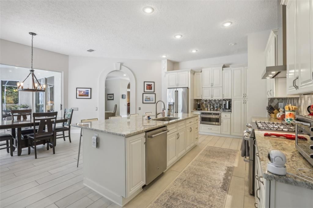 Kitchen with gas cook top and double ovens and a huge eat at kitchen island with sink