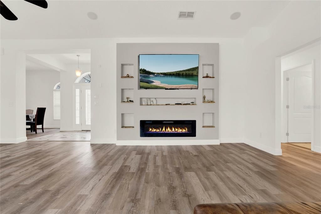 Entertainment area w/ wooden pocket shelves and detailed lighting around the border of the shelves.