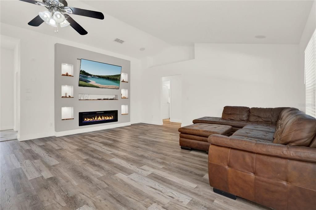 living room with entertainment area lit up and ceiling fan