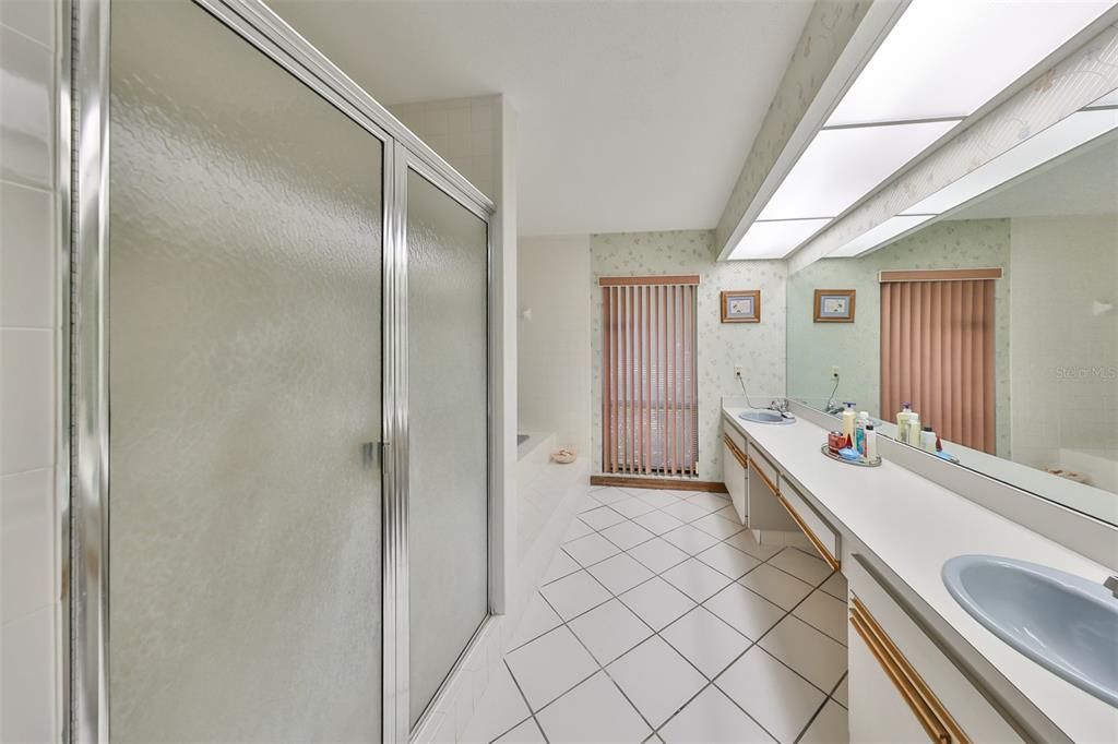 Primary ensuite bathroom with dual sinks, soaking tube, private toilet room and a window for natural sunshine