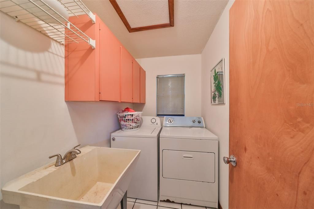 Laundry room has utility sink and shelving