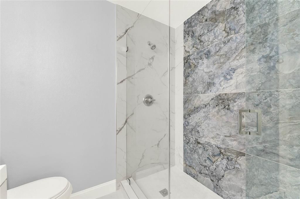 PRIMARY EN-SUITE BATH - remodeled to include a modern vanity, decorative mirror and a stunning shower with custom tile work framed by seamless glass!