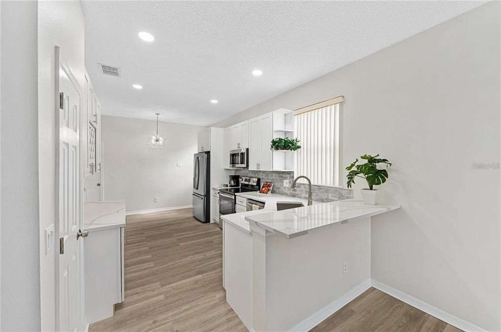 Kitchen, raised bar; plentiful quartz countertops for preparing, serving and entertaining; kitchen window; luxury vinyl floor