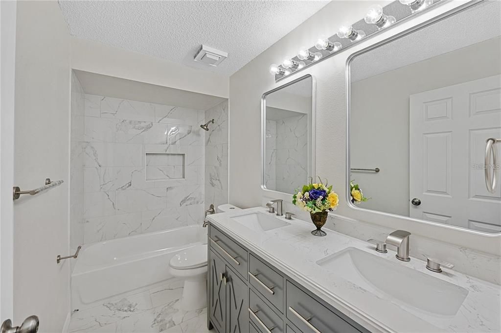 Tastefully remodeled second floor bath; Modern double sinks, fixtures and cabinets, and marble-like porcelain tile, giving a light and bright look.