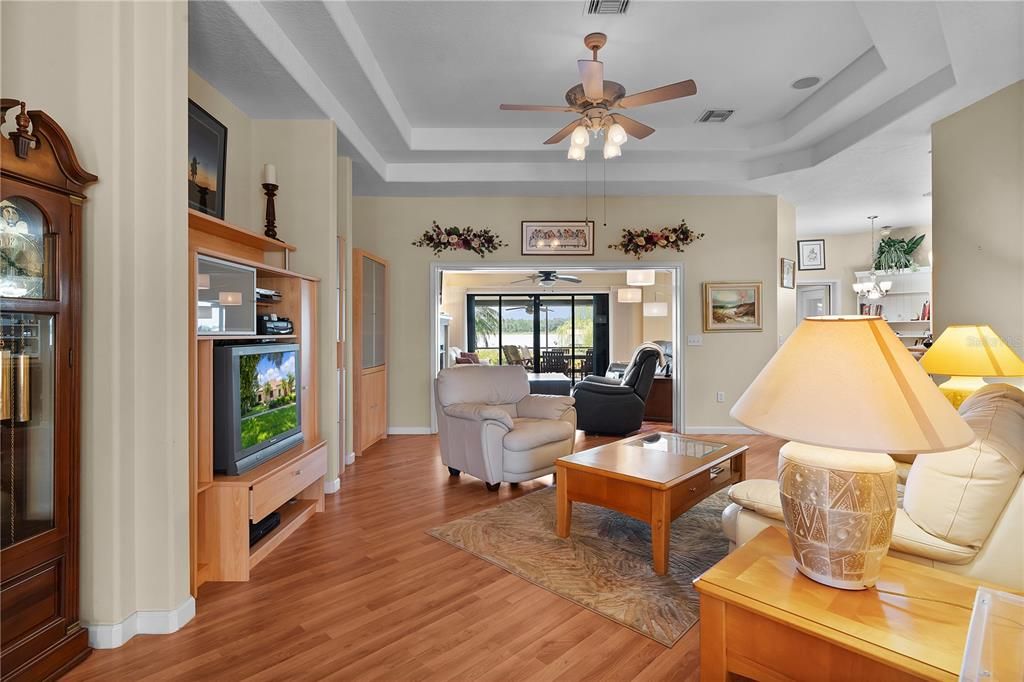 This spacious area features a stunning tray ceiling, beautiful wood flooring, and a ceiling fan, all enhancing the room’s elegance and comfort.