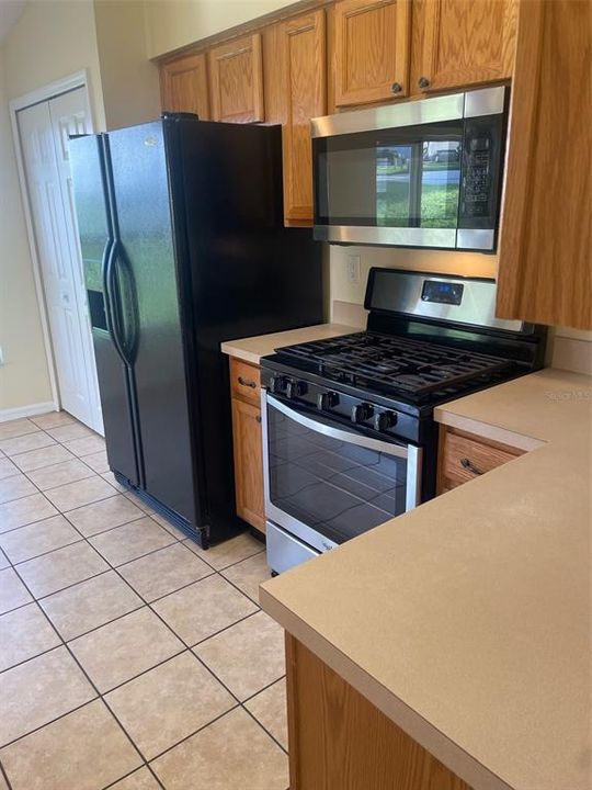 Kitchen has a gas range, over the range microwave oven and side by side refrigerator freezer with ice and water on the door.