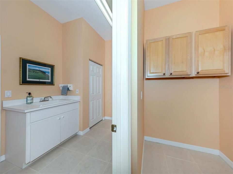 The laundry room is spacious with a utility sink, large closet, cabinetry, and additional storage area