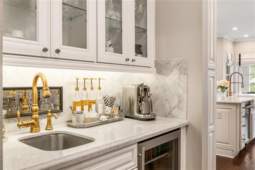 Delightful Coffee Bar & Wine Fridge, part of the Butler's Pantry has marble backsplash and under cabinet lighting.