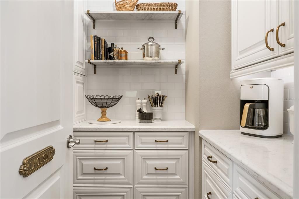 Super Cute Butler's Pantry off the Kitchen has marble shelves and under cabinet lighting.