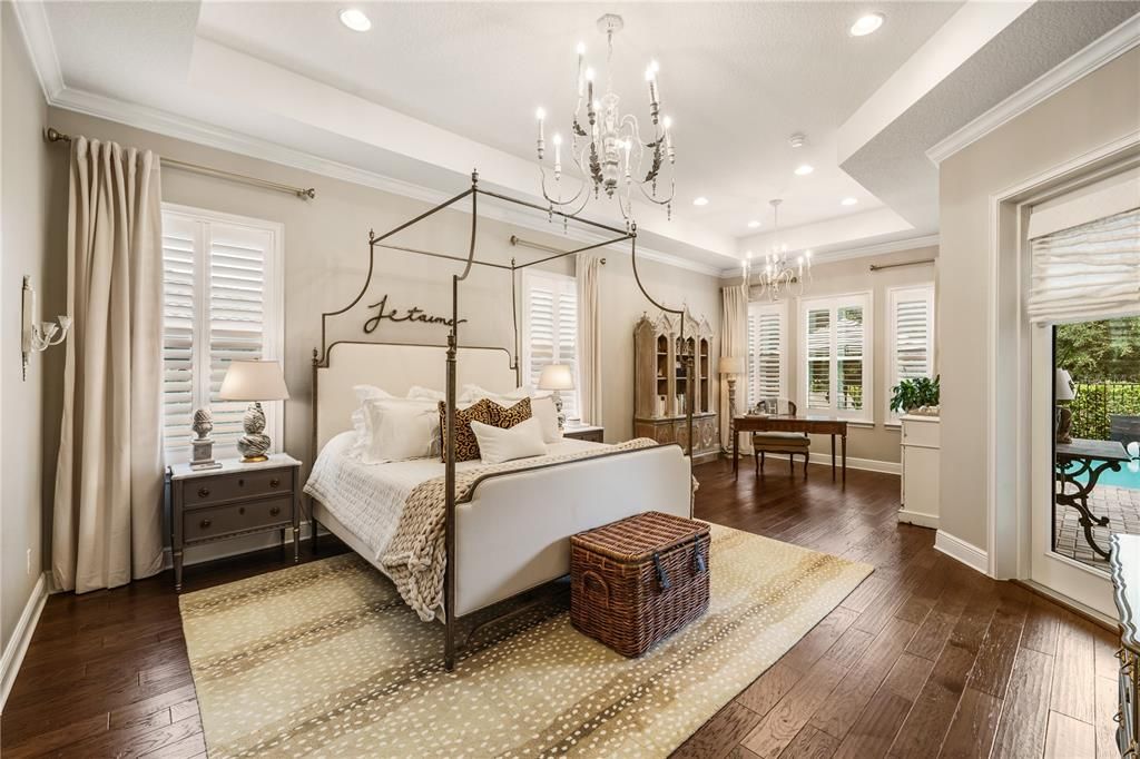 Spacious primary bedroom (24x16) with oak flooring, trey ceiling, crown molding and plantation shutters