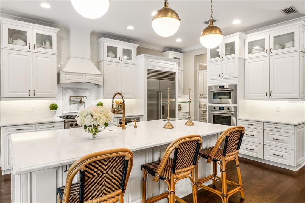 Counter-to-ceiling subway tile, abundant lighting, crown molding, quartz countertops, upper cabinets include breakfront crowning cabinets with reverse crown molding