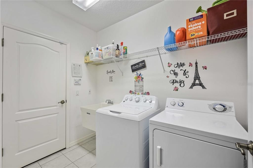 Laundry Room connects to garage with oversized utility sink with shelving for closet with ample storage.