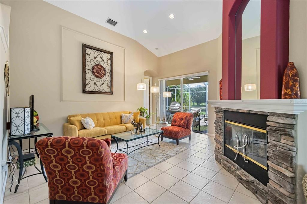 Living area in center of home with high ceilings, gas fire place and sliding glass doors leading out to the lanai.