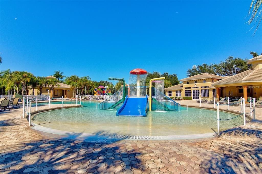 Community East pool with water slide, splash pad, heated pool and spa, outdoor covered lanai brick paver area for lounging pool side