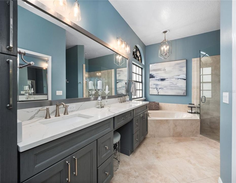 Primary bathroom with dual sinks, makeup vanity, walk in closet, garden tub and travertine finished shower.