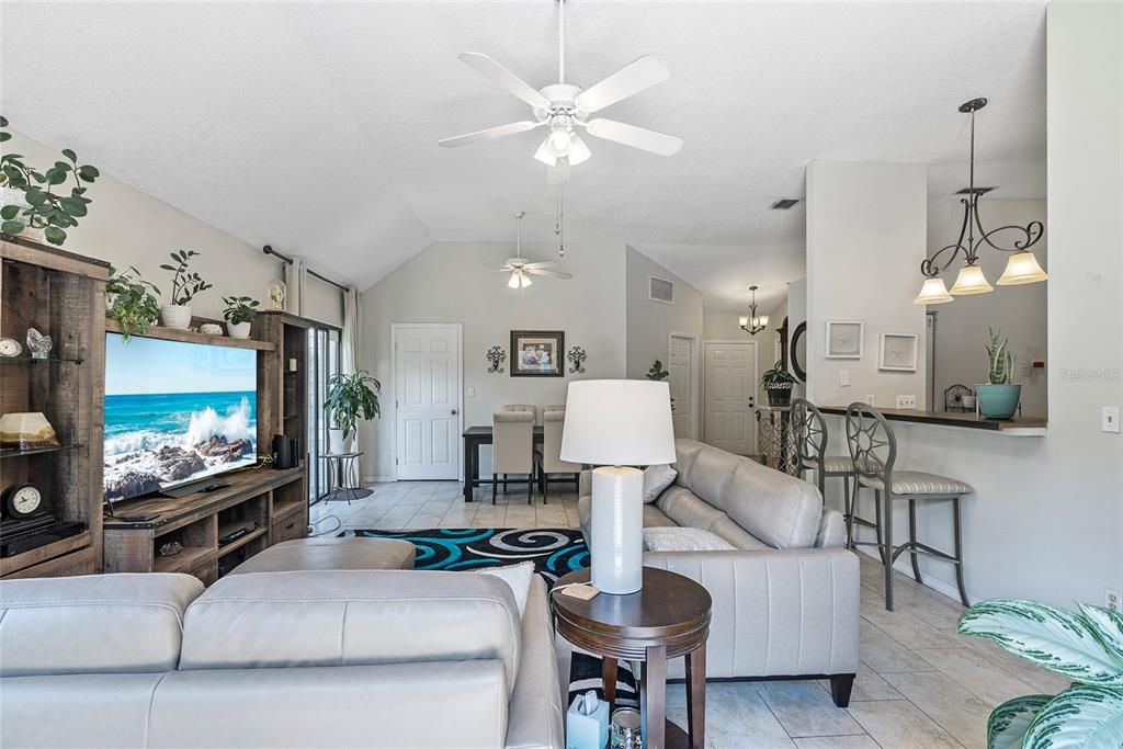 View of the living room, dining room & kitchen.  Door to the laundry closet is the closed door on the left side of the photo next to the sliding glass doors.  The door on the angled wall leads to the 2-car garage and the door to the right of the garage entry is the front door